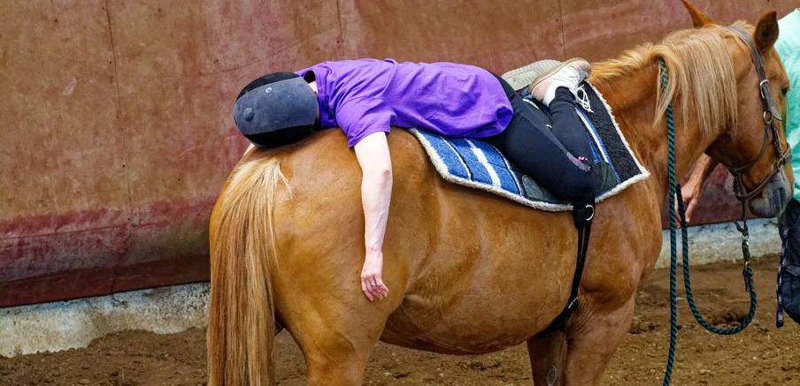 Personne détendue, allongée sur un cheval